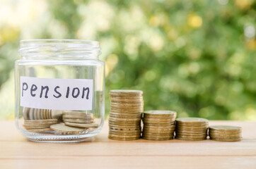 Glass jar with label PENSION and coins on wooden table. Space for text