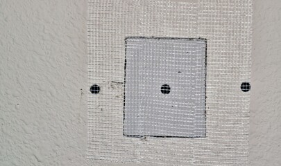 Drywall repairs in wall, fiberglass tape covering a square repair panel screwed in for support. Copy space on the left side of image. Repair, DIY home maintenance, step by step.