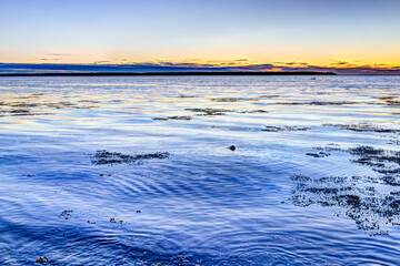 Sunset in Rimouski, Quebec by Saint Lawrence river in Gaspesie region of Canada with seaweed in...