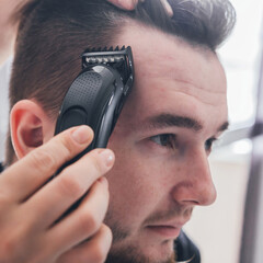 man with a beard cuts and cares for the hair himself in a quarantine coronavirus pandemic covid 19, the concept of stay home, a home hairdresser