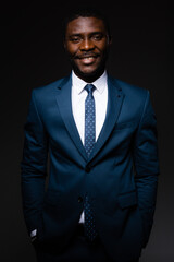 Portrait of an african american businessman man in blue classic suit who stands on gray background