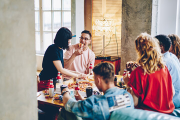 Group of youthful diverse hipster guys enjoying live communication during gathering leisure and PIZZA TIME in home apartment, multiracial friends tasting delivered fast food during weekend lunch