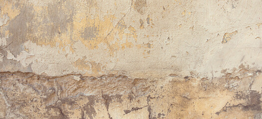 Old cracked weathered painted wall banner background texture. Yellow dirty peeled plaster wall with falling off flakes of paint