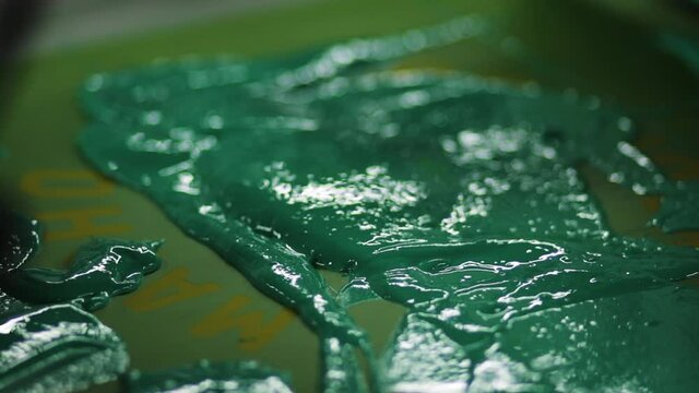Screen printing ink with squeegee. Green and yellow paint on press