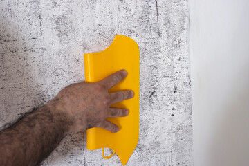 The Builder levels the glued Wallpaper with a plastic spatula. Close-up