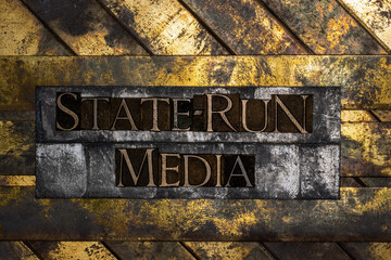 State-Run Media text formed with real authentic typeset letters on vintage textured silver grunge copper and gold background