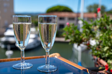 Summer party with sparkling champagne wine and sail boats haven of Port Grimaud on background, Provence, France