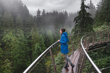 Canada Autumn travel destination in British Columbia. Asian tourist woman walking in famous attraction Capilano Suspension Bridge Park in North Vancouver, canadian vacation for tourism.