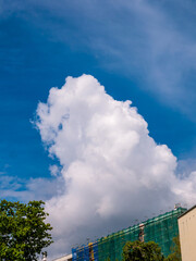 Massive cloud - towering cumulus - forming over building under construction with scaffolds and...