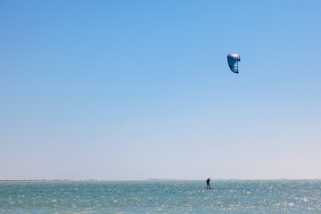 People practicing Kitesurfing. Colorful kites on the sea shore. Blue sea and windsurfing.