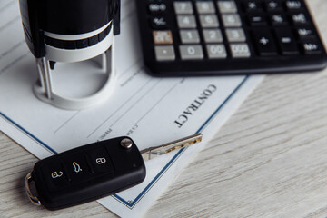 Purchase agreement for a car with contract, stamp, calculator and key close-up. Concept for sale...