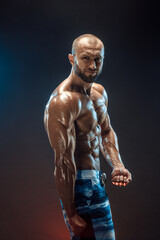 Fototapeta na wymiar Handsome strong bodybuilder posing in studio on black background.