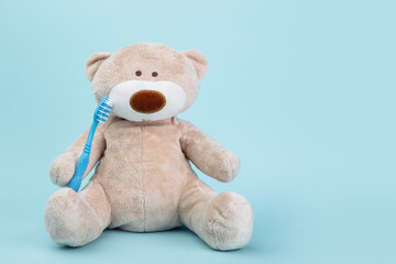 Stuffed Bear animal with toothbrush isolated on blue background. Children dentist theme.