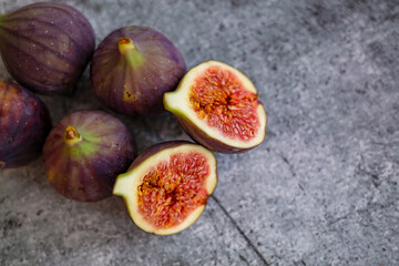 Whole and cut fresh vibrant figs fruit from above. A few figs freely lying on table. Fresh figs. Food Photo. whole and sliced figs on beautiful rustic background.