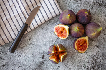 A few figs freely lying on old table. Fresh Organic Figs. Fresh purple fig fruit and slices in the kitchen. Fresh autumn fruit figs . Healthy food on rustic background