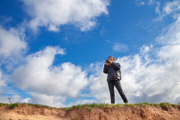 a tourist girl with a backpack and a camera walks along the river Bank on a Sunny day, taking pictures of the landscape, autumn