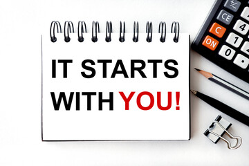 it starts with you, text on white paper, on a light background, near a pencil and calculator