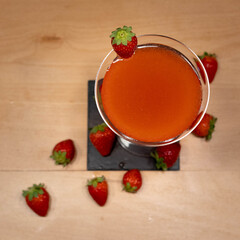 Strawberry Cocktail in martini glass with strawberry in garnish on wood table from above and with strawberries