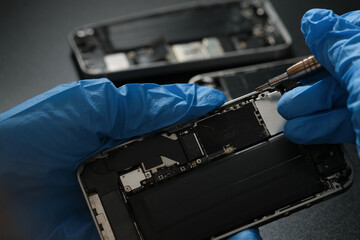 Technician repairing mobile phone at table, parts and tools for recovery repair smartphone's...