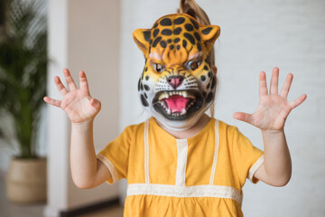 Child play at home in animal role. Little girl wearing a tiger mask.