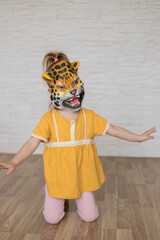 Child play at home in animal role. Little girl wearing a tiger mask.