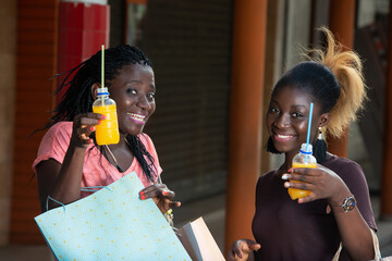 Close-up of young girls with fruit juice bottles after shopping, happy.