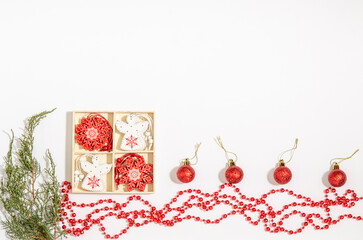 Christmas tree toys white angel, red snowflake in a wooden box, red beads, juniper branches, balls on a white background. Space for copy space, flat lay.