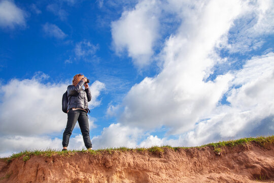 a tourist girl with a backpack and a camera walks along the river Bank on a Sunny day, taking pictures of the landscape, autumn
