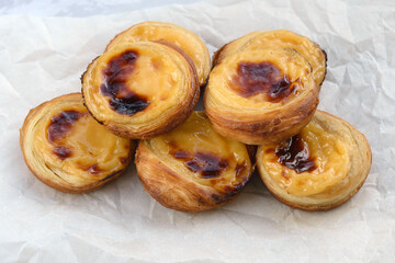 Traditional Portuguese popular dessert Pastel de nata or Pastel de Belem on a white wooden board. Delicious puff pastry cups with custard. Gastronomic travel in Portugal.