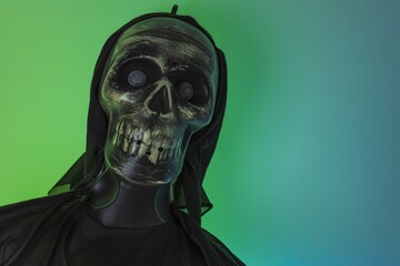 Close up view of black lighted skeleton figure on green-blue background. Halloween concept. 