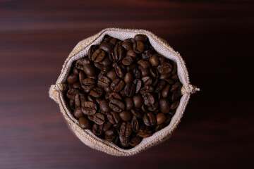 Fototapeta premium Kaffeebohnen in einem Leinenbeutel von Oben auf dunklem Tisch