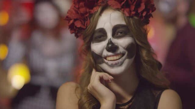 Slowmo portrait shot of beautiful woman wearing halloween costume smiling and posing for camera at party