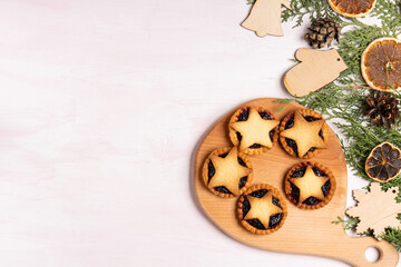 Christmas homemade mince pies on wooden paddle board on pink wooden background