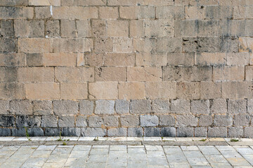 Exterior detail of an old Mediterranean historic building, stone wall facade and street.