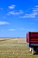 Fototapeta premium A grain truck sits in a wheat field waiting to be loaded as a combine approaches