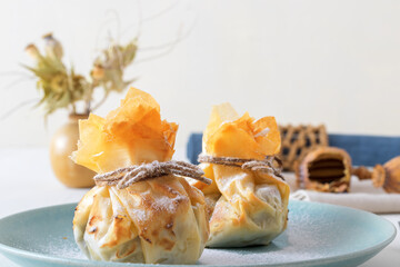 Plum and poppy seeds phyllo purses on a white wooden, delicious vegetarian dessert on a white wooden table.