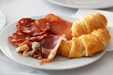 chopped bacon and croissants on a white plate