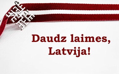 Ribbon in Latvian flag colors and Latvian traditional thunder cross sign on a white background with congratulatory message "Great happiness, Latvia!".
