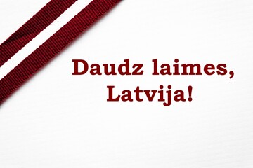 Ribbon in Latvian flag colors on a white background with congratulatory message "Great happiness, Latvia!".