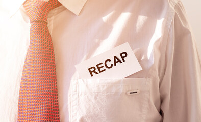 RECAP word inscription on paper card in pocket of male white shirt with red tie, close up