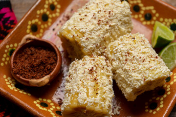 Mexican corn on the cob also called elotes with cheese and mayonnaise on wooden background