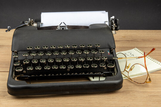 an old black portable typewriter with a steno pad and eye glasses as at a secretary's desk