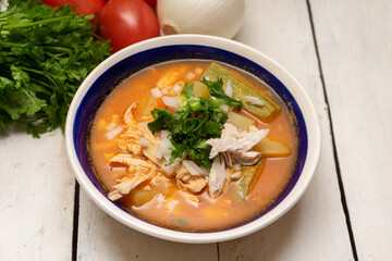 Mexican chicken soup with vegetables and rice on white background