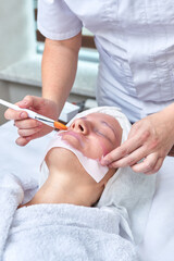 male beautician applies collagen. woman at a procedure for rejuvenation and skin care