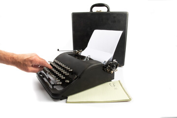 one finger typing on an old black portable typewriter isolated on white