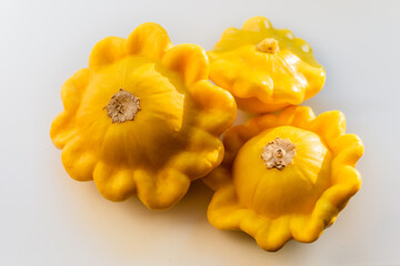 three yellow ripe squash lie on a white background in the light of the sun
