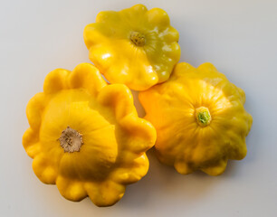 three yellow ripe squash lie on a white background in light of sun