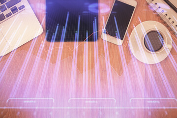 Double exposure of financial chart hologram over desktop with phone. Top view. Mobile trade...