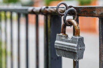Rusty padlock on the door. Closed old locked gate. Closed lock on the grating fence
