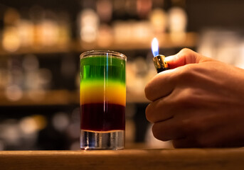Beautiful tricolor cocktail. Red green yellow alcoholic drink standing on the bar counter,...
